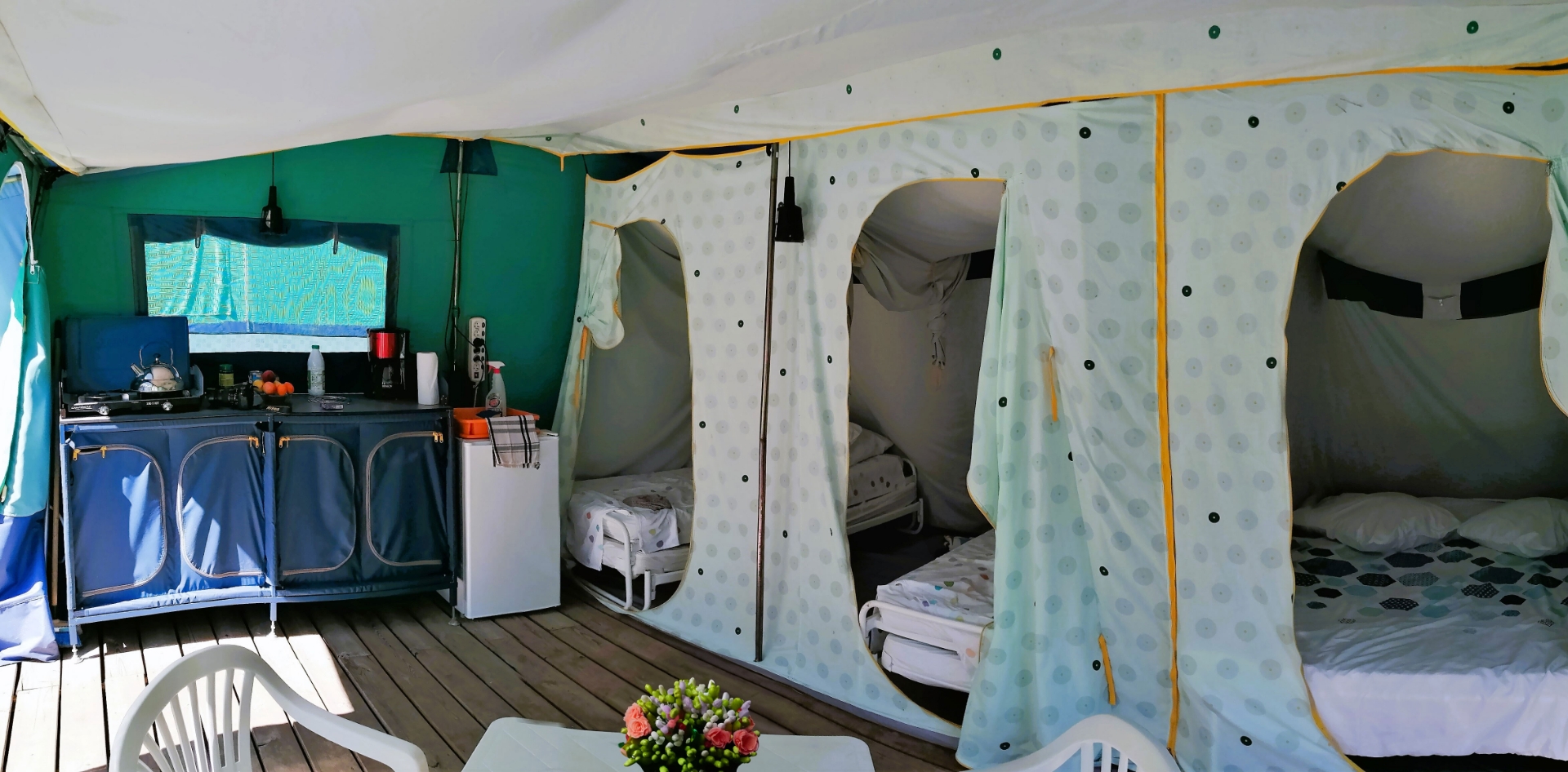 Der Küchen-/Essbereich und die Schlafzimmer des Zeltbungalows, zu vermieten auf dem Campingplatz Les Bords de Loue in der Region Bourgogne-Franche-Comté