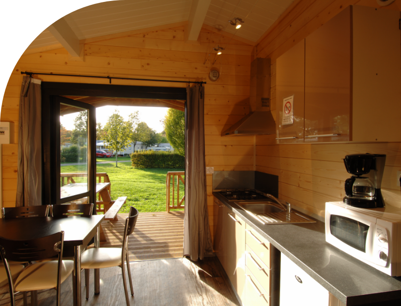 Kitchen area and living room in the Monia Chalet to rent at Les Bords de Loue campsite in Jura