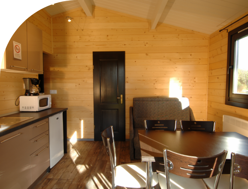 L’Espace salon - salle à manger du chalet Monia en location au camping les Bords de Loue, en région Bourgogne-Franche-Comté