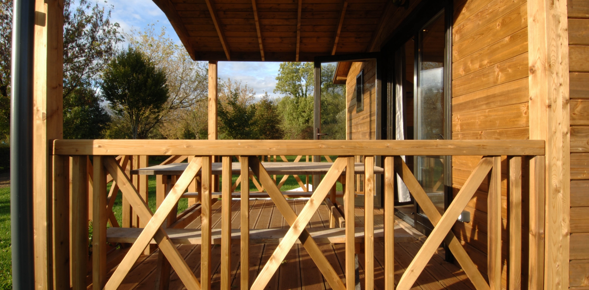 La terrasse en bois couverte du chalet Monia en location au camping les Bords de Loue, en région Bourgogne-Franche-Comté