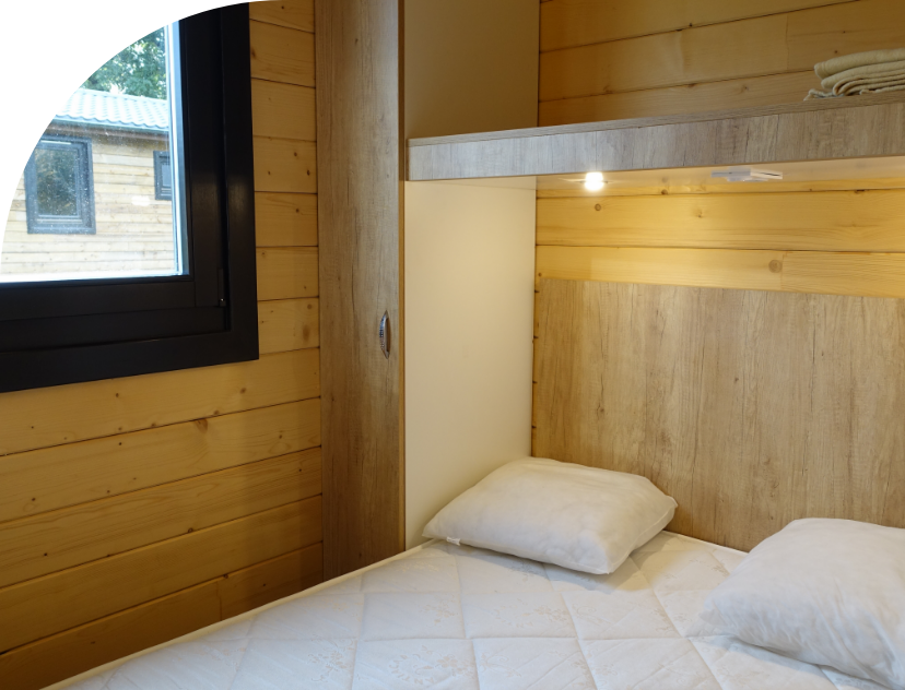 Schlafzimmer mit Doppelbett des Chalets Savania, zu vermieten auf dem Campingplatz Les Bords de Loue im Jura