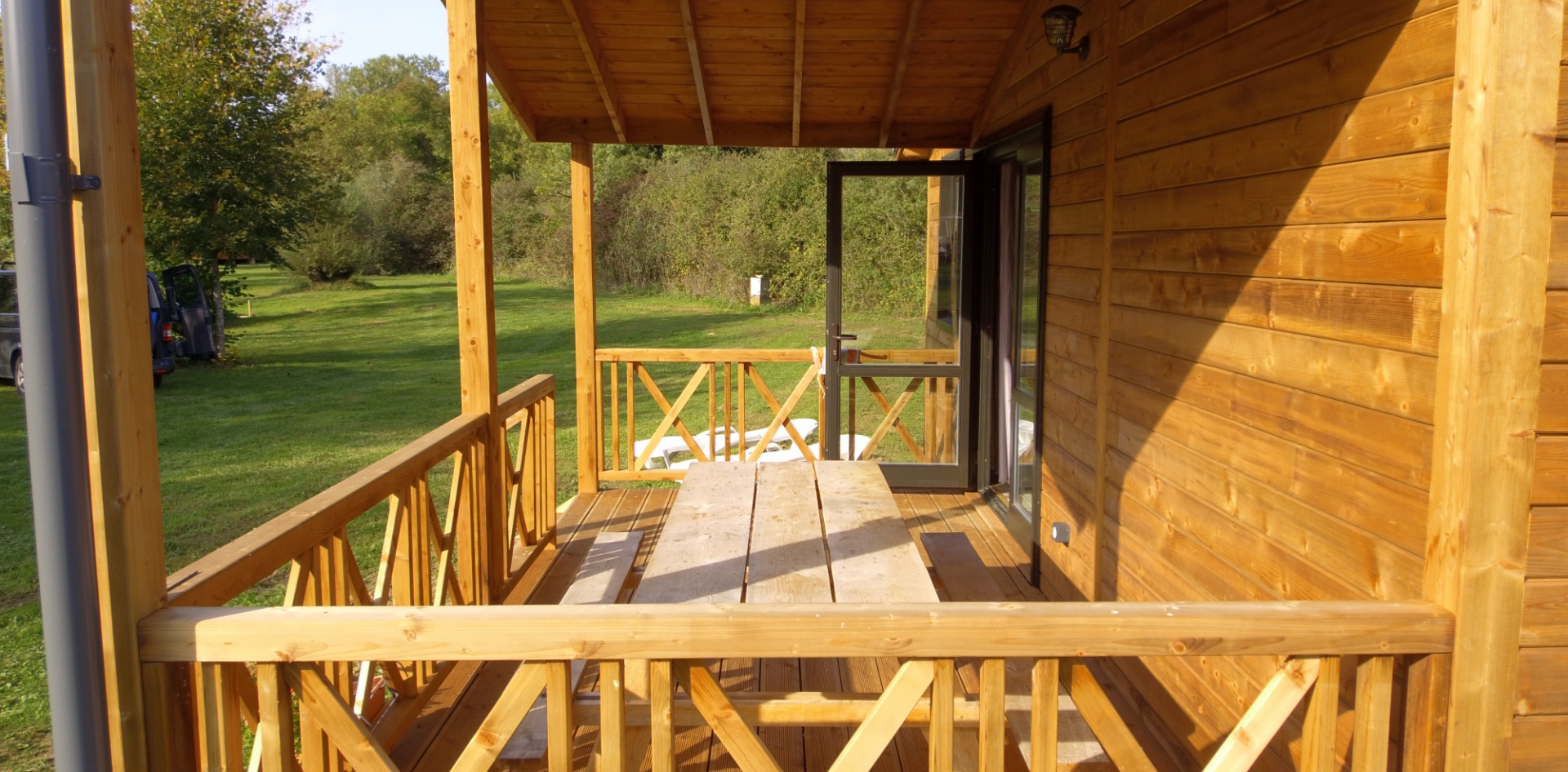 La terrasse en bois couverte du chalet Savania en location au camping les Bords de Loue, en région Bourgogne-Franche-Comté