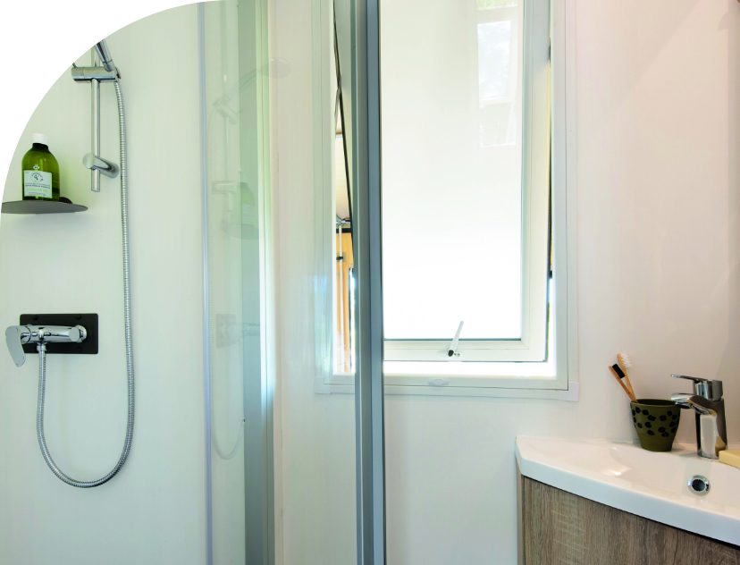 The bathroom in Coco Chrono with shower and wash basin, original accommodation to rent at Les Bords de Loue campsite in Jura