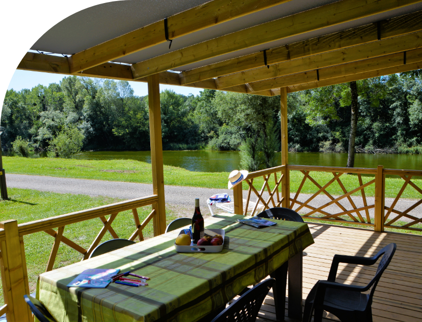 La terrasse en bois couverte du mobil-home Family en location au camping les Bords de Loue dans le Jura