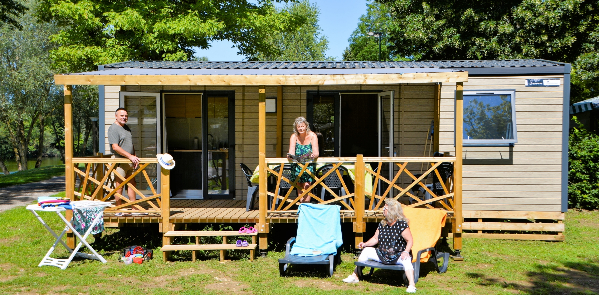 Vue du mobil-home Family avec terrasse en bois couverte en location au camping les Bords de Loue en région Bourgogne-Franche-Comté 