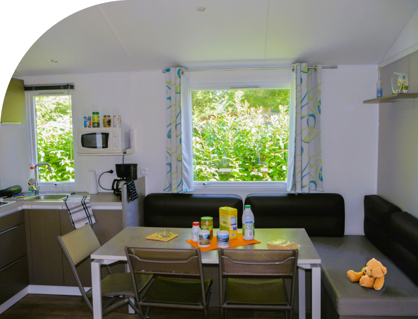 Espace salon – salle à manger du mobil-home Trio en location au camping les Bords de Loue dans le Jura
