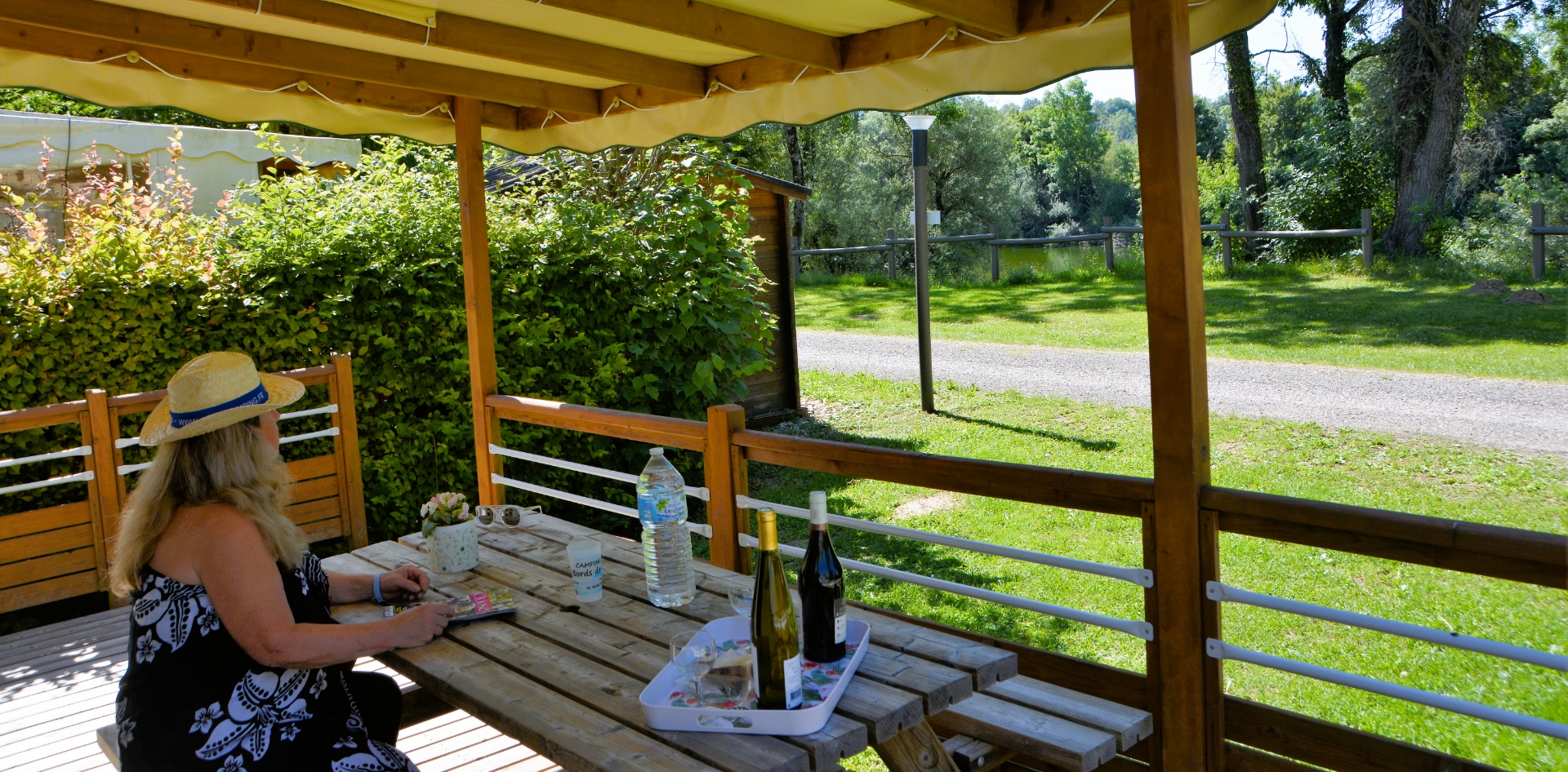La terrasse en bois du mobil-home Trio en location au camping les Bords de Loue dans le Jura